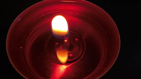 Burning tealight candle against dark background, flickering flame creating warm Stock-Footage 342617678