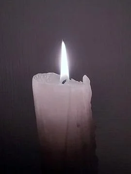 Burning thick white candle on a plain gray background Foto stock