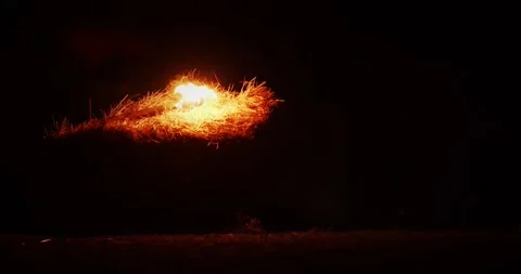 Burning torch is falling on a hay bale in the dark, night, 4k Stock Footage 143828997