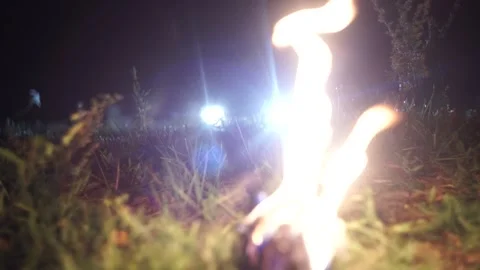 A burning torch lies on the grass in the light of car headlights Stock Footage 170658641