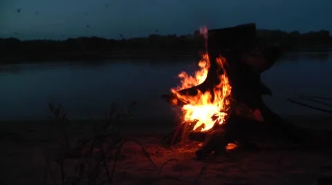Burning tree stump on the beach by the river at night Stock Footage 45882688