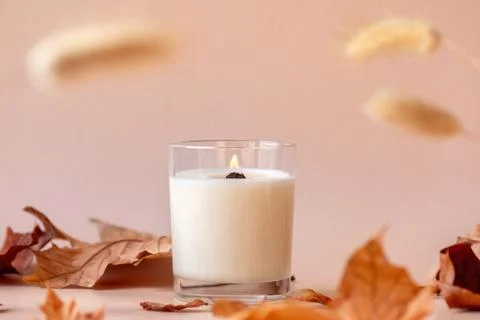 Burning vanilla candle on beige background. Aesthetic autumn composition with Stock Photos