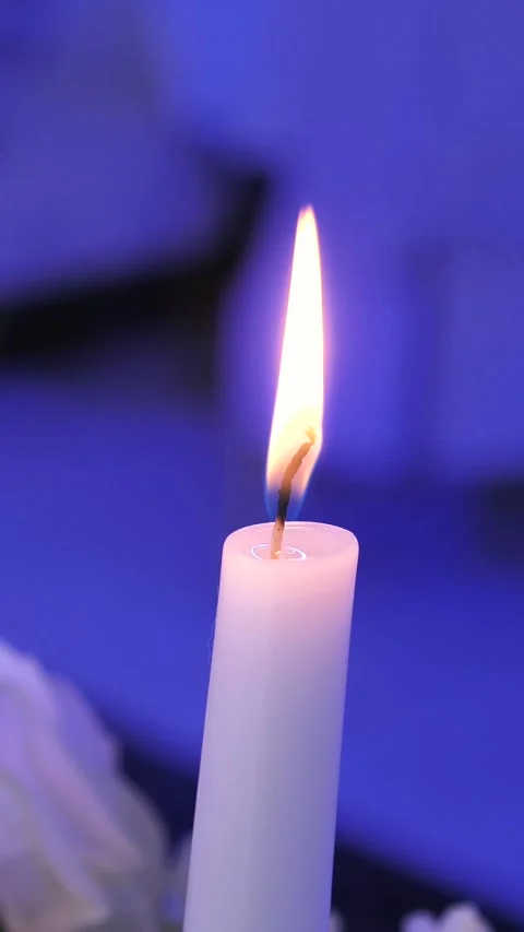 Burning white candle close-up with blue background lighting Vídeos de archivo 345639022