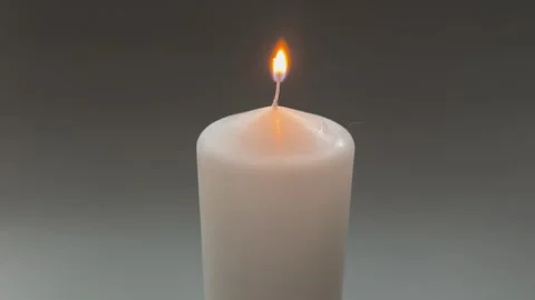 Burning white paraffin thick round candle on gray background Stock Footage 328052301