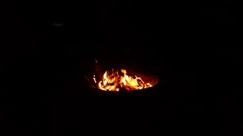 Burning wood in fire pit at night in back yard surrounded in total darkness Stock Footage 196947489