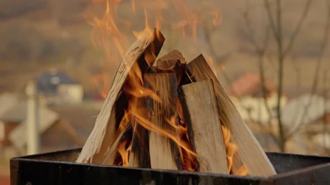 Burning wood logs creating glowing embers inside metal brazier Stock Footage 302476573
