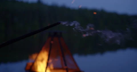 Burning wood stick / Campfire pit by the lake at night Stockbeeldmateriaal 130927770