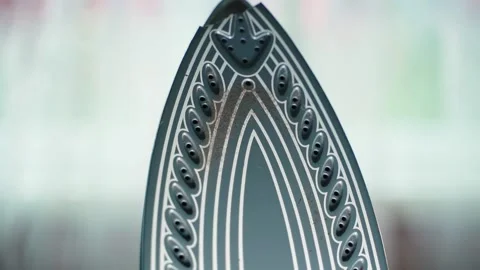 Burnt and impacted soleplate of a laundry iron, close-up on a blurred background Stock Footage 235907715
