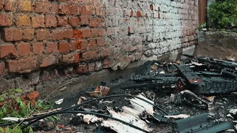 Burnt debris lies scattered next to a brick wall following a recent fire Stock Footage 339095968