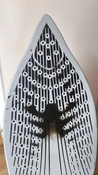 Burnt dirty surface of a steam iron soleplate close up Stockfoto's