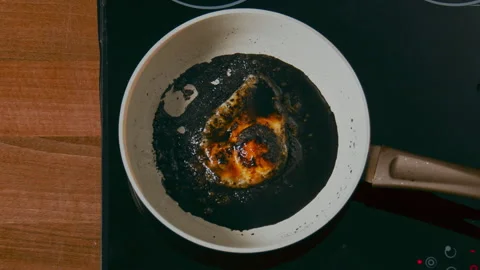 Burnt egg on a white pan in black oil on a black stove. top shot 100fps Vídeos de archivo 196233137
