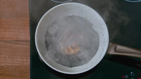 Burnt egg on a white pan in black oil on a black stove. top shot 100fps Stock Footage 196275111