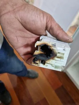 Burnt electrical component in hand Stock Photos