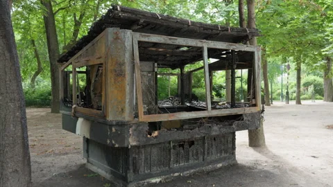 Burnt kiosk stands destroyed by fire in a city park after a street protest Stock Footage 337295459