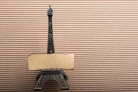 Burnt piece of paper on model Eiffel tower on cardboard 스톡 사진