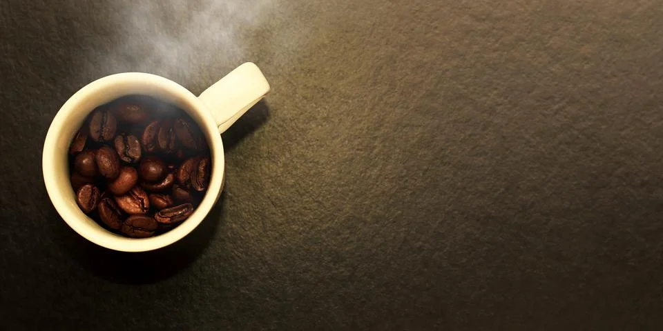Burnt raw roasted coffee seeds in the white mug and hot steam Stock Photos