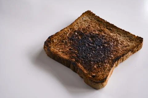 Burnt slice of toast bread isolated on white with text space Stock Photos