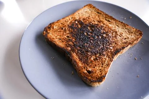 Burnt slice of toast bread isolated on white with text space Stock Photos