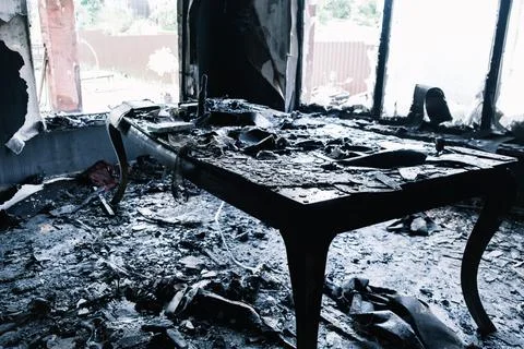 Burnt table and broken windows covered in ash after a fire. Fire damage Stockfoto's