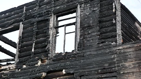 Burnt timber wall and window frames of a house, representing disaster and loss Stock Footage 329956936