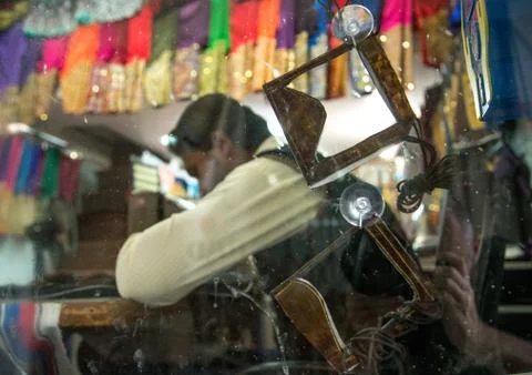 Burqas in front of a tailor using a sewing machine to make embroideries, Qeshm Stock Photos