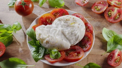 Burrata cheese surrounded by cherry tomatoes and basil leaves. Stock Footage 343940904