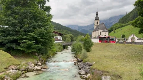 Bus arrives at stop in front of Parish Church of St. Sebastian. Ramsau, Germany Stock Footage 341423572
