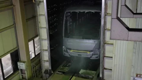 Bus body shell moving through an industrial spray booth for chemical treatment Stock Footage 332141847