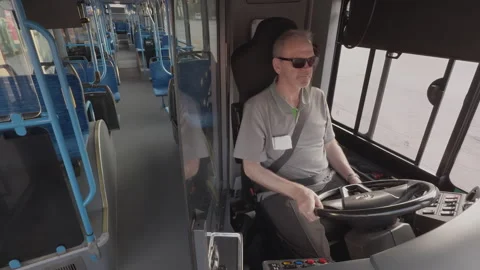 Bus driver operates vehicle in urban setting, interior view of public transport Vídeos de archivo 343689065