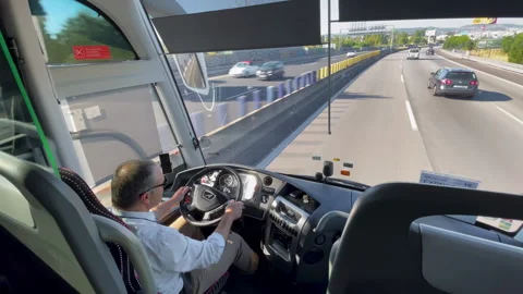 Bus Driver at Wheel on Highway, Front View Inside Public Transit Vehicle Stock-Footage 318471828