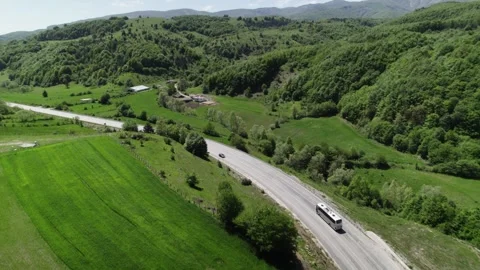 A bus driving on the highway between green mountains Stock Footage 262379858