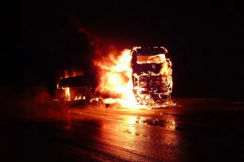 Bus Engulfed in Flames During Large Vehicle Fire at Night Stock Photos