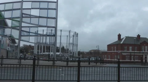 Bus passing modern stores and gasometer with old red brick pub to right. Stock Footage 1091902