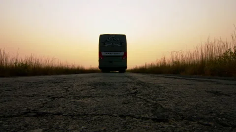 A bus passing over a camera at sunset in the middle of a country road. Stock Footage 168663277