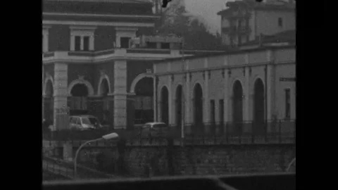 A bus passing, two people walking in front of a station, 8mm film, bolex d8l Vidéo 149821156