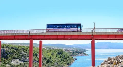 The bus rides over the bridge located above the sea bay on a summer day, near Stock Photos