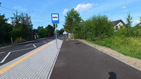 Bus stop and pedestrian path along suburban road on sunny day. Bicycle POV Stock Footage 341974745