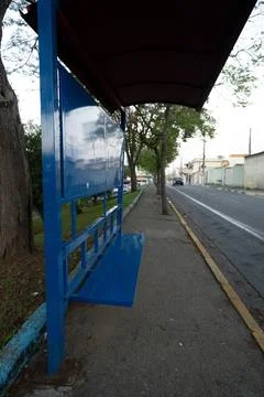 Bus stop with cover and empty steel seat in quiet neighborhood Stock Photos
