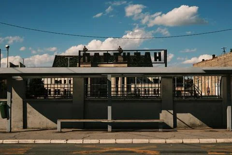 Bus stop with shadow patterns and metal bench. Partizan sign in Cyrillic script Stock Photos