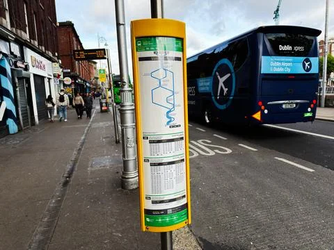Bus stop with timetable and Dublin Express coach at city curb for Dublin Ai.. Stock Photos