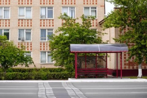 Bus stop without people on the background of a brick building. Stock Photos