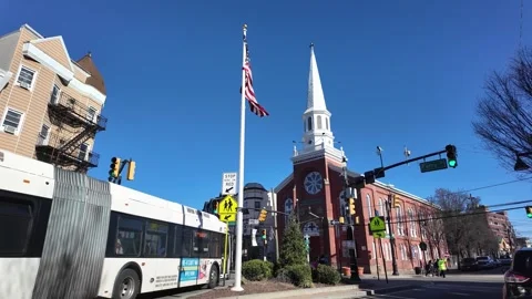 A Bus Stops at a Busy Intersection in Front of a Church on a Sunny Day Stock Footage 279028281