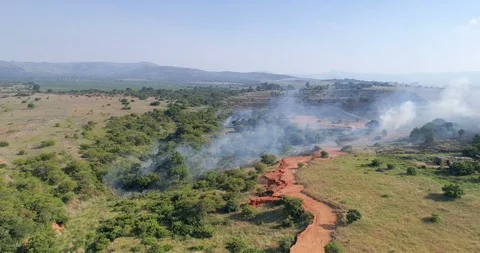 Bush fire in an African gully spewing white smoke choking nearby settlement Vídeo Stock 85955009