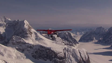 Bush plane flying over a snowy mountain range and glacier Stock Footage 335096842