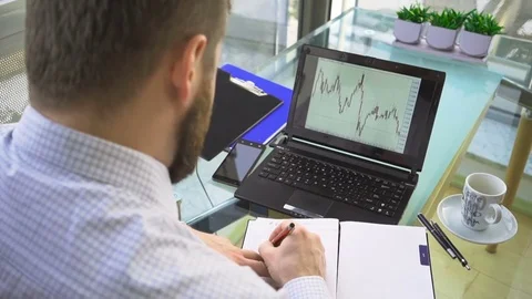 Busienessman analyzing chart, laptop computer, make notes, drink coffee, office Vidéo 73167372