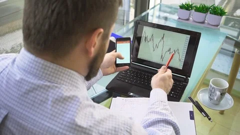 Busienessman analyzing chart on laptop computer, browsing smartphone, office 库存影片 73167690