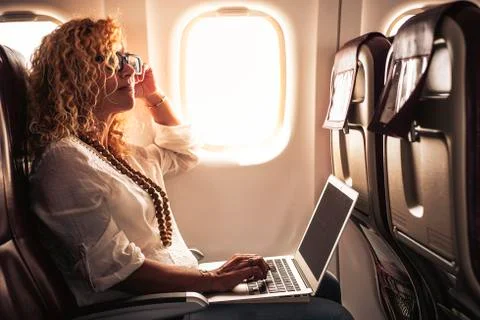Business adult beautiful curly blonde woman travel on airplane connected to i Stock Photos