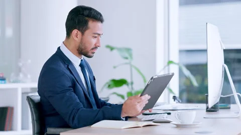 Business analyst comparing statistics on a digital tablet while researching Stock Footage 254980896