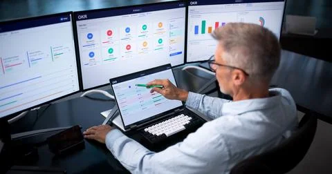 Business Analyst Reviews Performance Data On Laptop During Team Meeting. Stock Photos