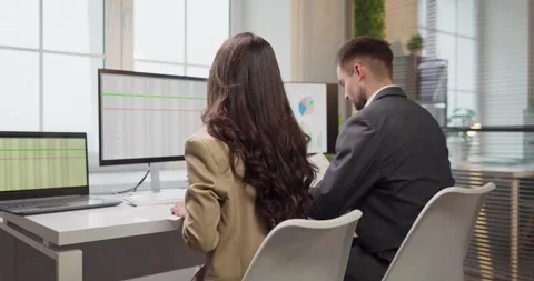 Business analysts reviewing financial data on monitors in modern office Stock Footage 326128111